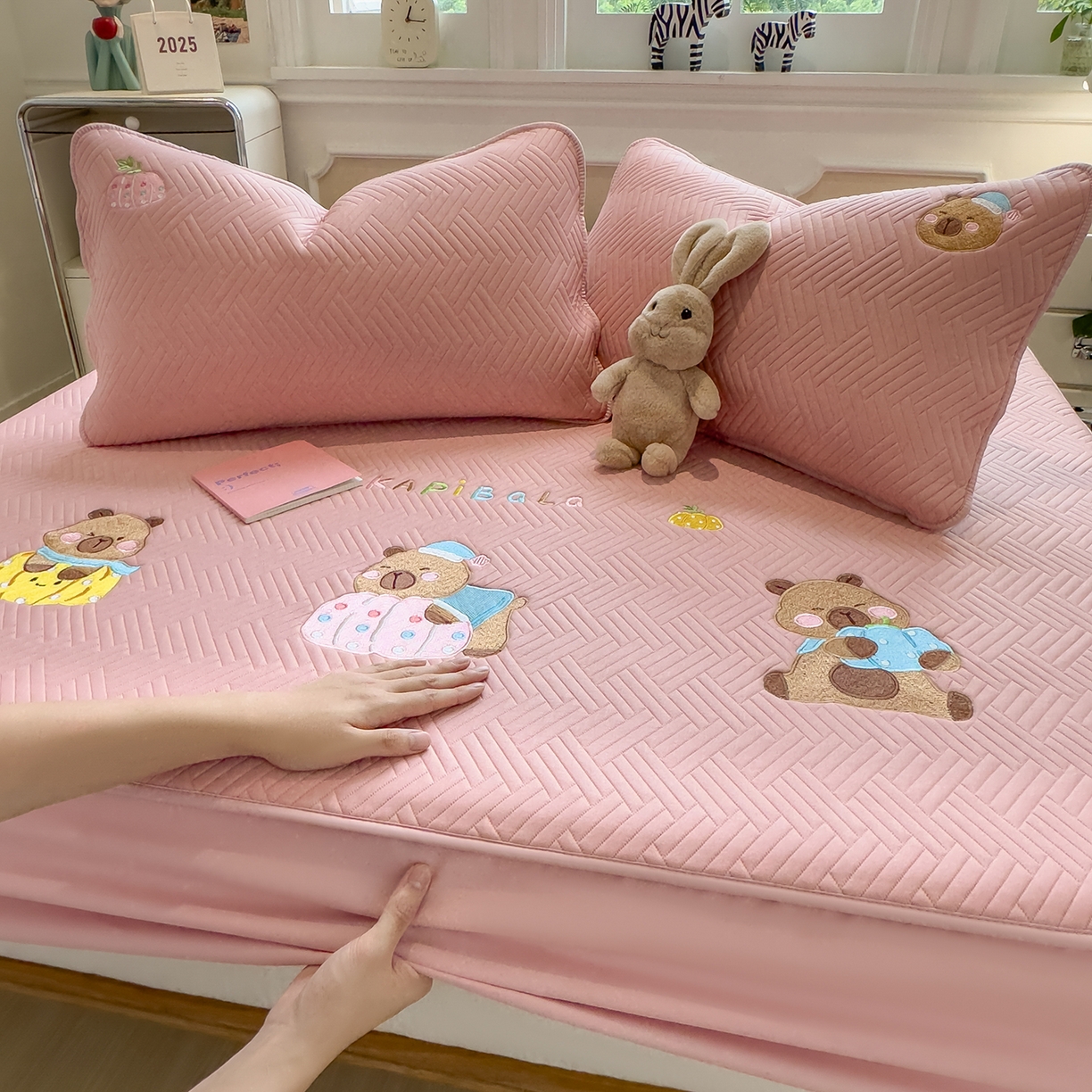 91家纺网 家纺一手货源 找家纺 眠多宝 2025新款三联刺绣卡通夹棉床笠全包围床垫保护套 欢乐卡皮巴拉-藕合粉