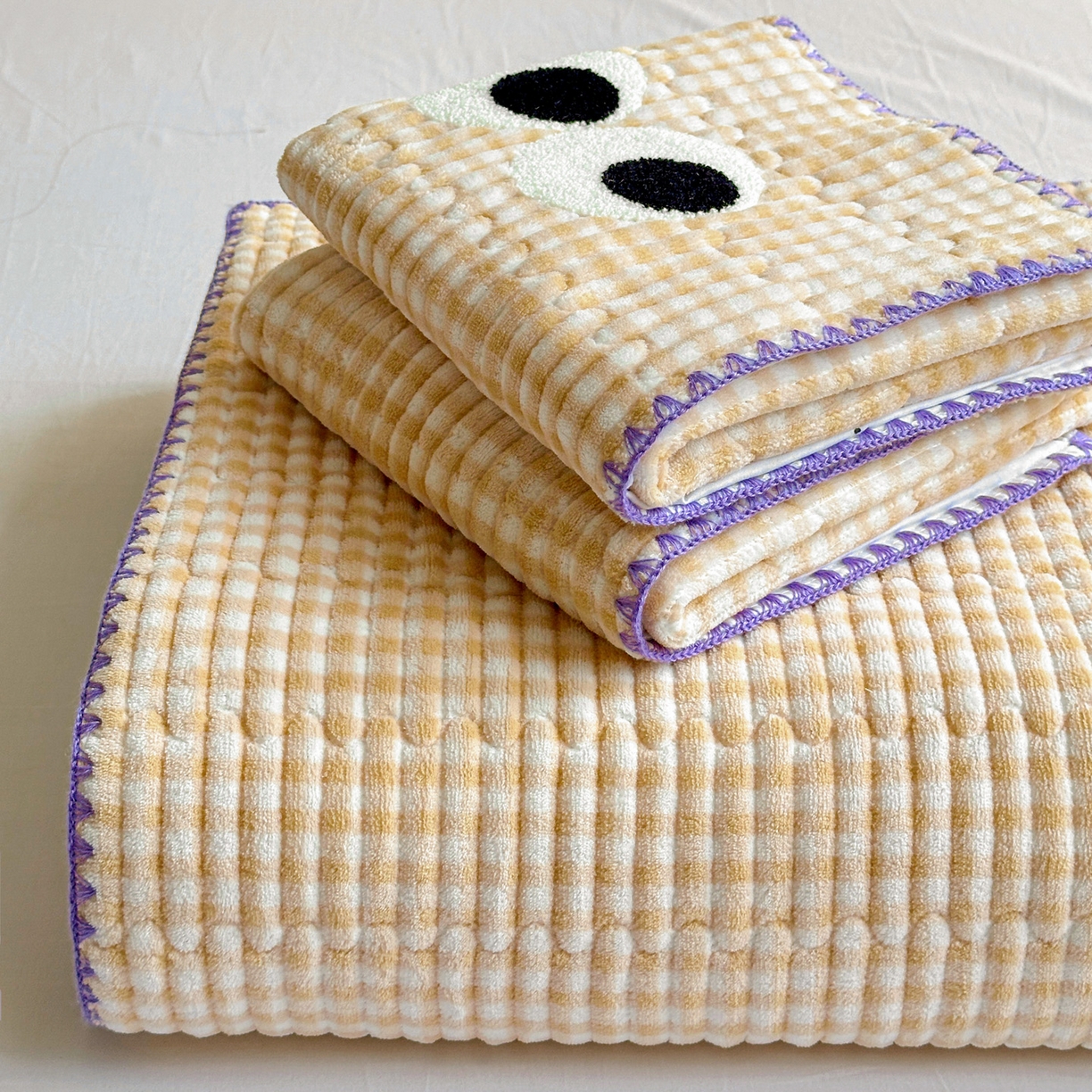 91家纺网 家纺一手货源 找家纺 格真 2025新款无印风贝壳绣三角针牛奶绒床盖三件套大眼萌枕套双面可用 米黄小格