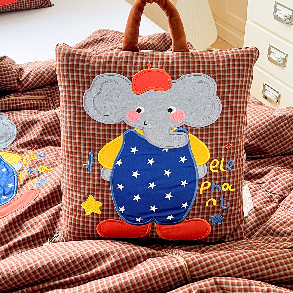 91家纺网 家纺一手货源 找家纺 古本家居 2026春夏新款全棉小丑象系列抱枕被 全棉小丑象红格